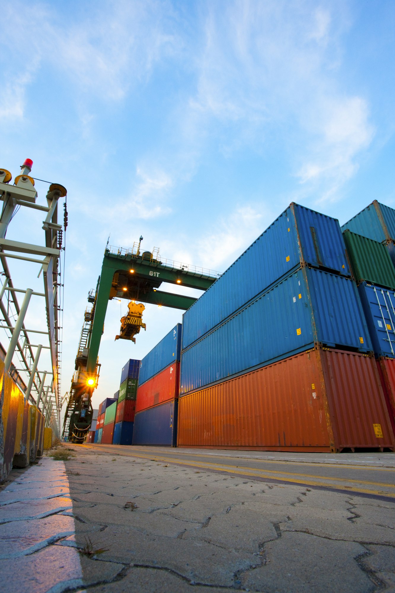 Cranes and multi-colored stack of cargo containers at dusk